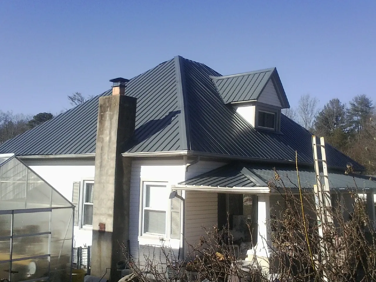 Dark blue standing seam metal roof on a white farmhouse with dormer — Slate & Tile Roof Repair by Roofing Brothers in Honey Brook