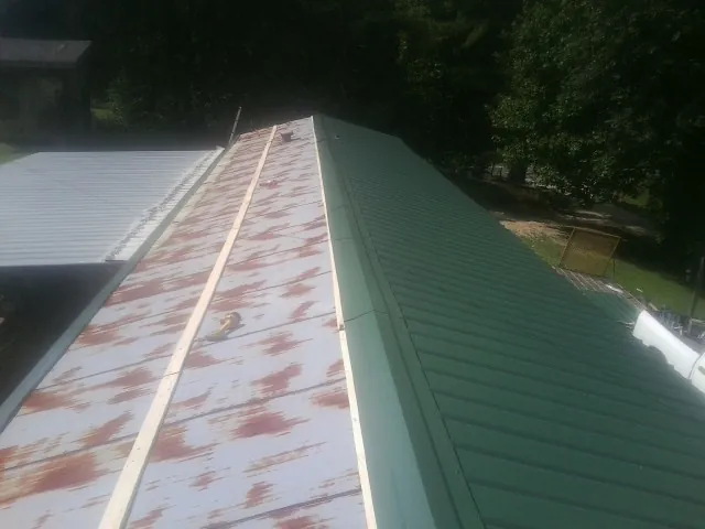 Old rusted panels beside newly installed green metal roofing — Wind Damage Roof Repair by Roofing Brothers in Honey Brook