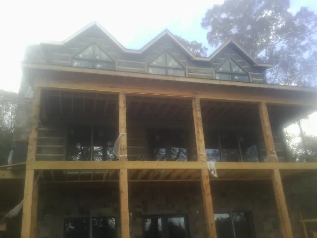 Dormers and porch framing on a large log home under construction — Roof Coating work by our crew in Honey Brook