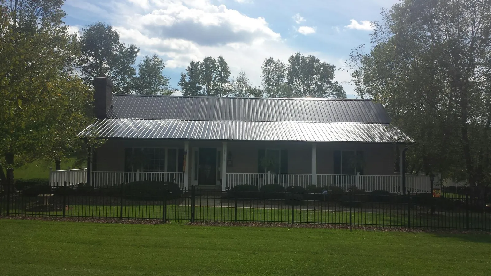 Gray metal roof on a brick ranch with a full width front porch — Gutter Guard Installation work by our crew in Honey Brook