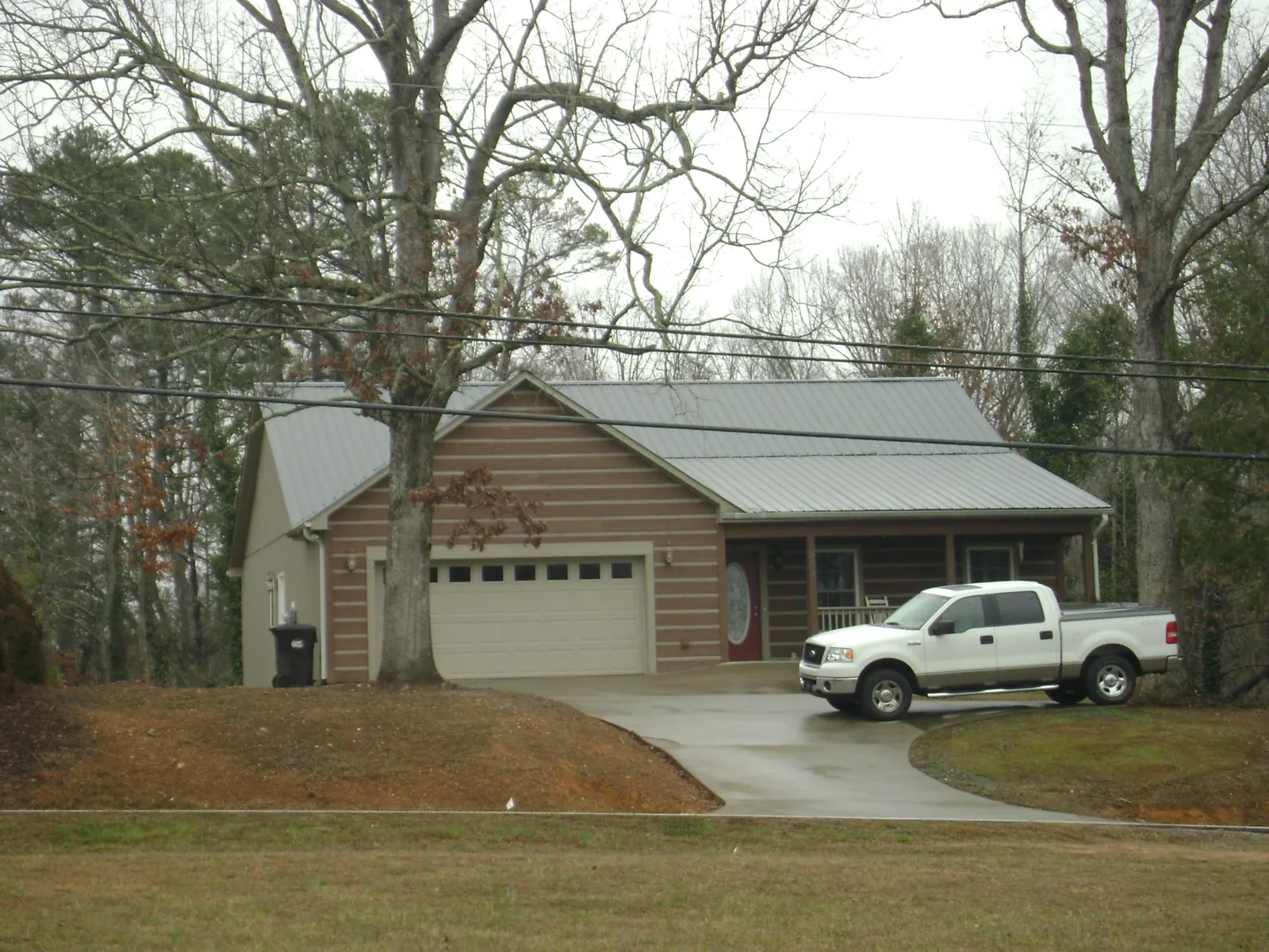 Gray metal roof on a log sided house with an attached two car garage in Honey Brook