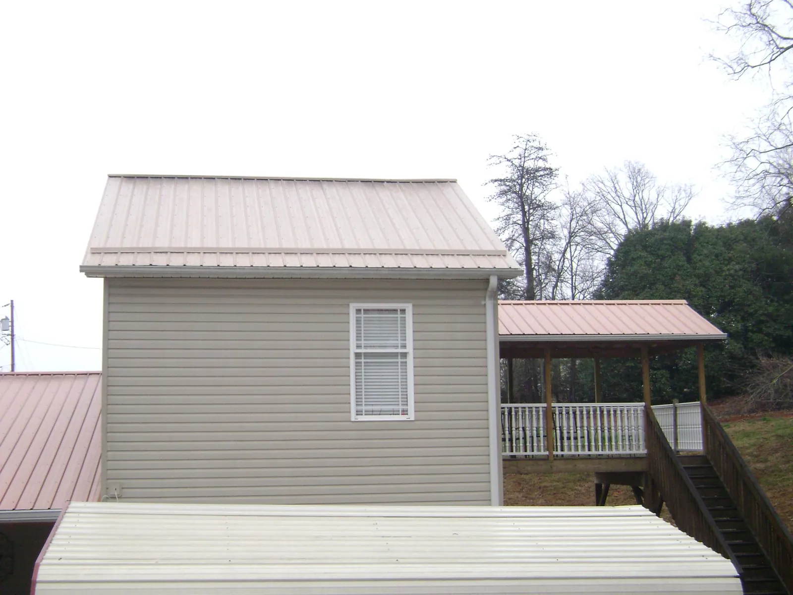 Tan metal roofs on a two story addition and attached porch, from a Roof Replacement job in Honey Brook