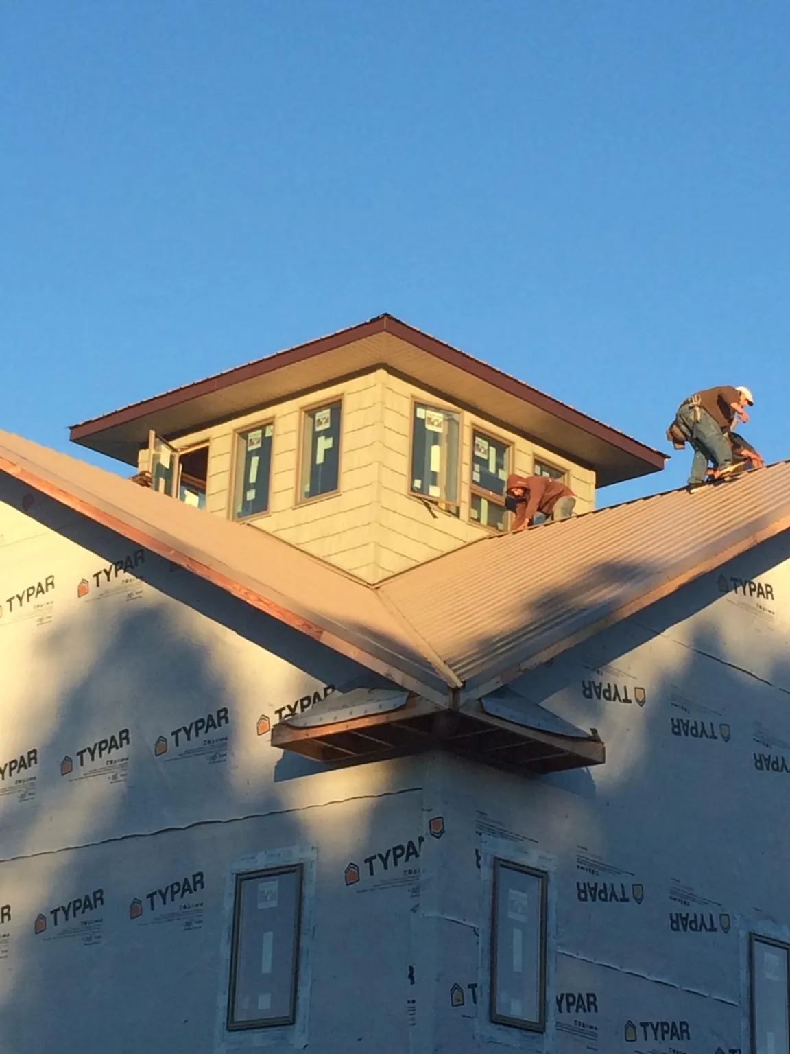 Roofers working around a rooftop cupola on a new metal roof at sunset — Roof Waterproofing in Honey Brook by Roofing Brothers
